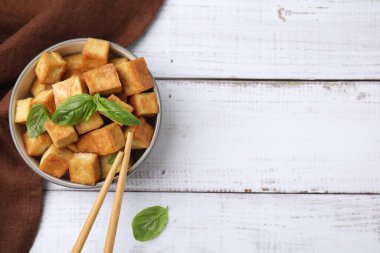 Lezzetli kızarmış tofu ve fesleğenli kase beyaz ahşap masa, düz yatak. Metin için boşluk
