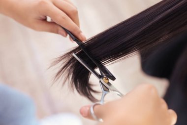 Güzellik salonunda kadın saçını kesen profesyonel kuaför, yakın plan.