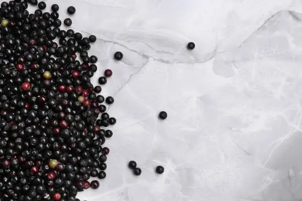 stock image Pile of tasty elderberries (Sambucus) on white marble table, flat lay. Space for text