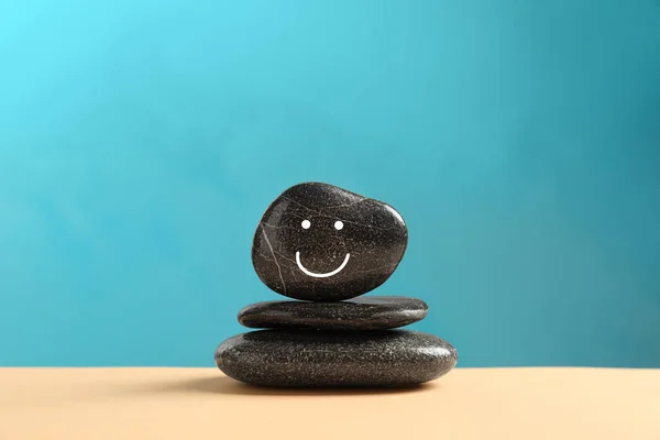 Stack Stones Drawn Happy Face Beige Table Light Blue Background — Stockfoto