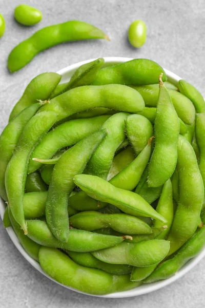 Green edamame beans in pods on light grey table, flat lay