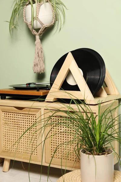 stock image Vinyl records and player on wooden cabinet near light green wall