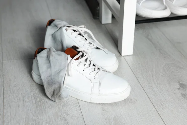 Sneakers with dirty socks on white wooden floor indoors