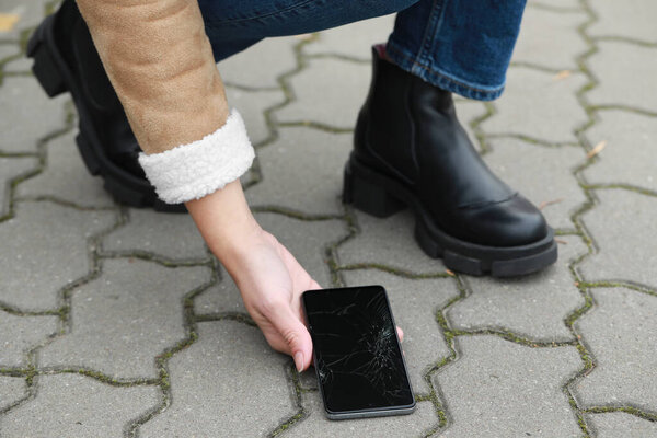 Женщина сбросила смартфон с тротуара, крупным планом. Ремонт устройств