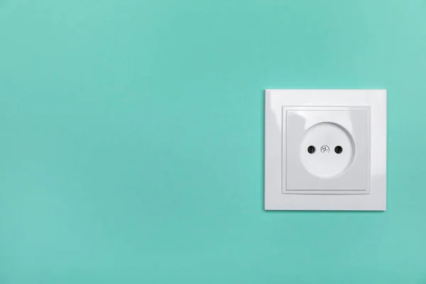 Power socket on turquoise wall, space for text. Electrical supply