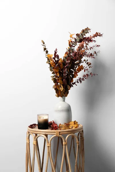 白い壁の近くのテーブルの上に枝やキャンドルの花瓶 ストックフォト