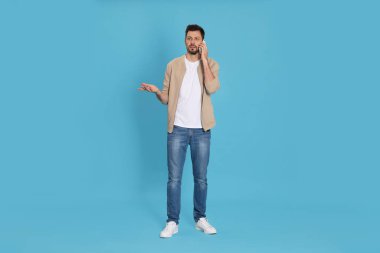 Telefonda konuşan adam açık mavi arka planda