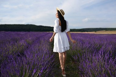 Beautiful young woman walking in lavender field