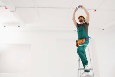 Elektrikçi kabloları kapalı alanda yalıtım bandıyla onarıyor.