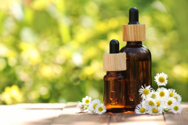 Ahşap masa üzerinde papatya uçucu yağ ve çiçek Şişeleri, metin için alan