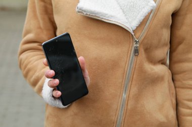 Dışarıda akıllı telefondan zarar görmüş bir kadın var, yakın plan. Aygıt onarımı