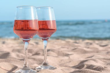 Deniz kıyısındaki kumda lezzetli gül şarabı bardakları, metin için yer