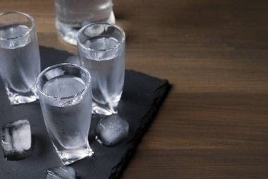 Tahta masanın üzerinde buz küpleri olan votka kadehleri. Metin için boşluk