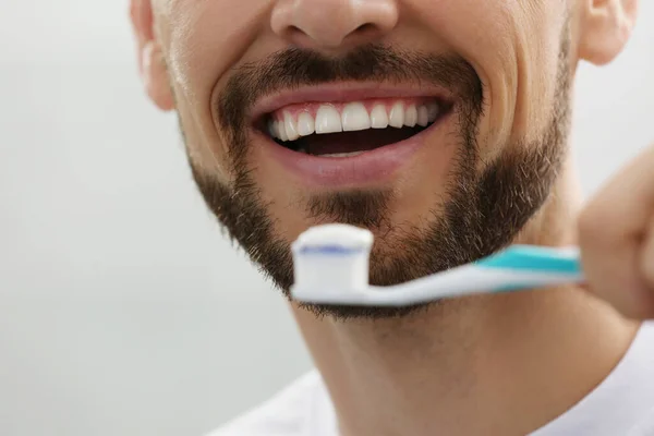 Mann Hält Bürste Mit Zahnpasta Auf Grauem Hintergrund Nahaufnahme — Stockfoto