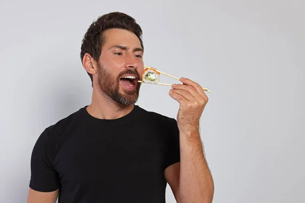 Bell Uomo Che Mangia Sushi Roll Con Bacchette Sfondo Grigio — Foto Stock
