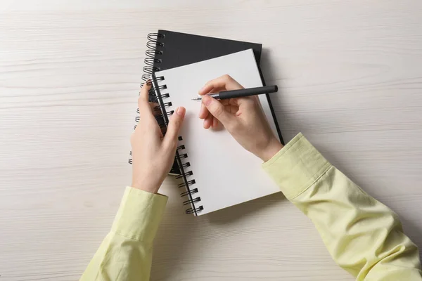 白い木製のテーブルでノートに書く女性 トップビュー — ストック写真
