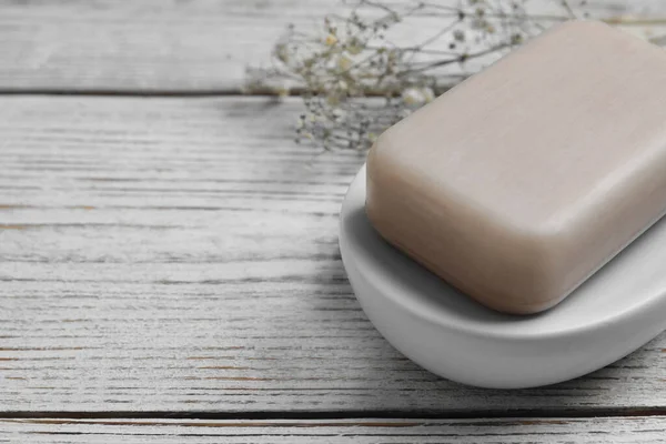 Dish with soap bar on wooden table, closeup. Space for text