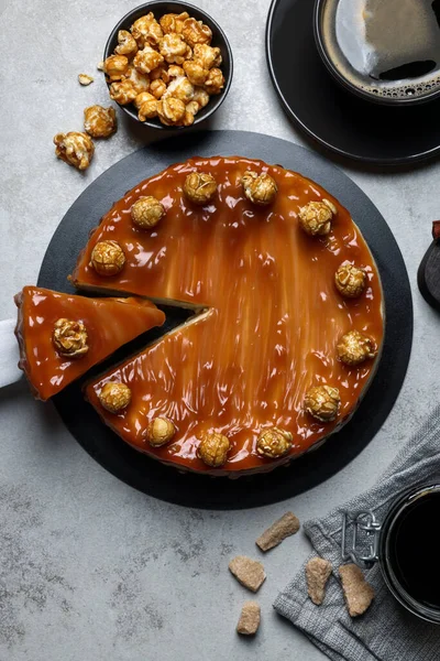 stock image Sliced delicious caramel cheesecake with popcorn served on light grey table, flat lay