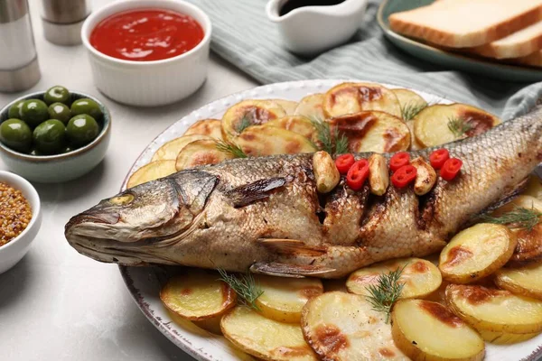 stock image Plate with delicious roasted sea bass fish and potatoes on table, closeup