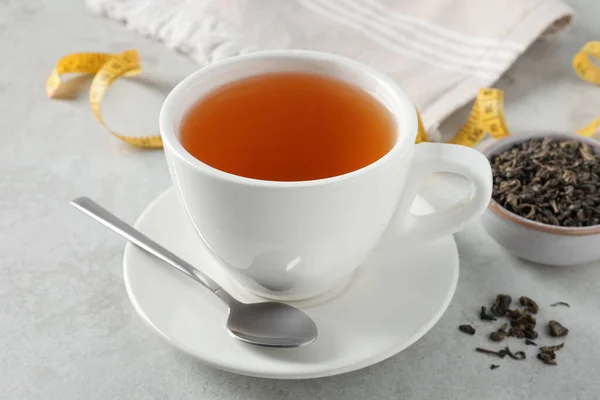 Cup of herbal diet tea on white table, closeup. Weight loss concept