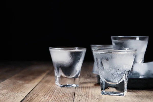 Skott Glas Vodka Med Isbitar Träbord Mot Svart Bakgrund Närbild — Stockfoto