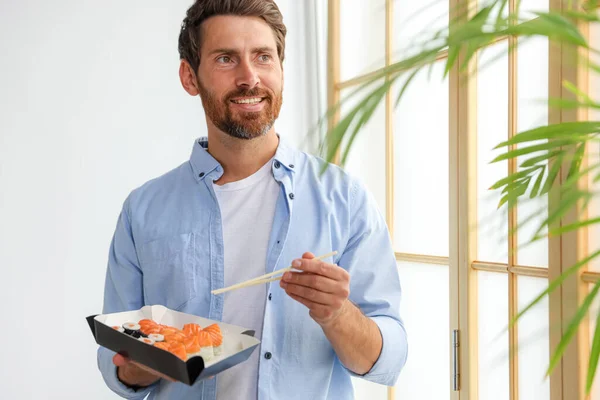 Šťastný Muž Jíst Sushi Rolky Hůlkami Uvnitř — Stock fotografie