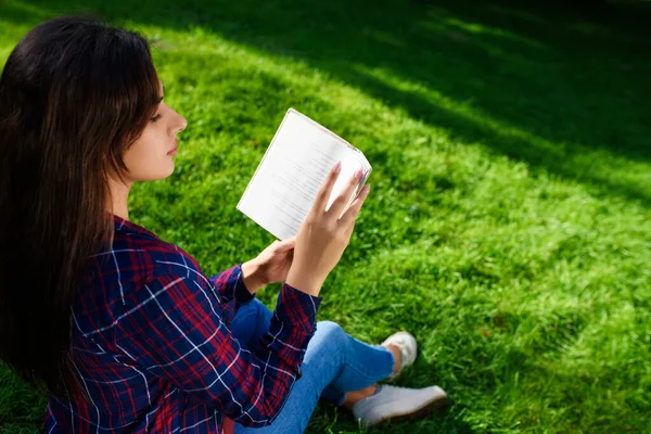 年轻女子在户外看绿草书 — 图库照片