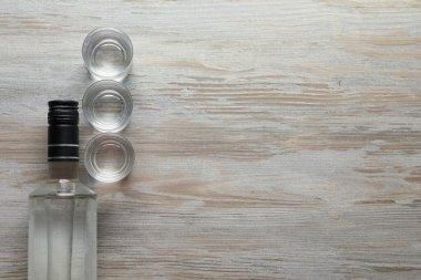 Şişe ve shot bardakları tahta masada, düz yerde. Metin için boşluk