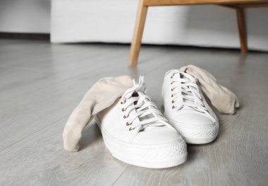 Beyaz ahşap zeminde kirli çorapları olan spor ayakkabıları.