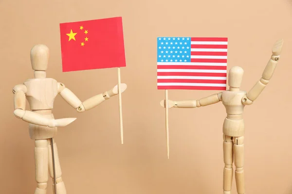 米色背景的木制人体模特 手持美国和中国国旗 贸易战 — 图库照片