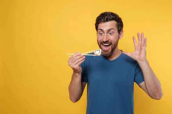 Homem Emocional Segurando Rolo Sushi Com Pauzinhos Fundo Laranja Espaço — Fotografia de Stock
