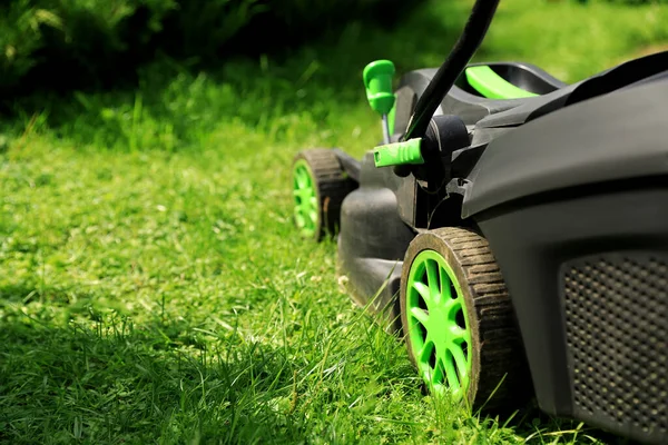 庭の緑の芝生の上に芝刈り機 テキストのスペース — ストック写真