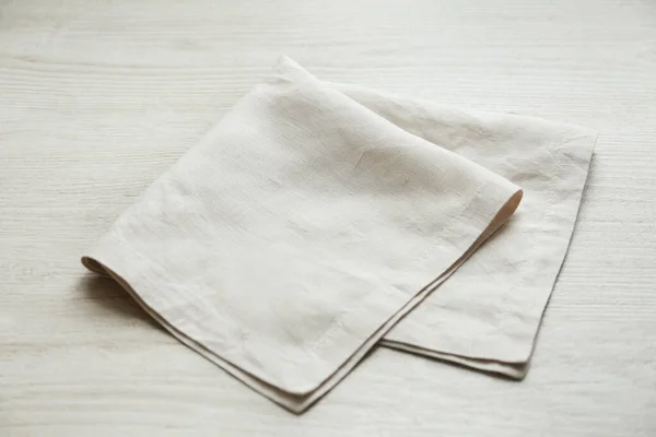 白い木製のテーブルの上に軽い折り畳まれたナプキン — ストック写真