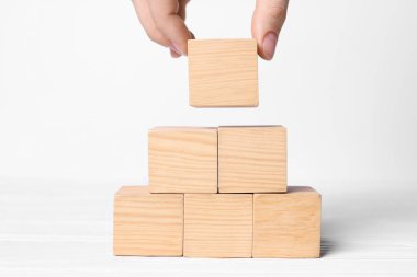 Beyaz arkaplana küp piramidi inşa eden bir kadın, metin için yeri olan yakın plan. Fikir kavramı