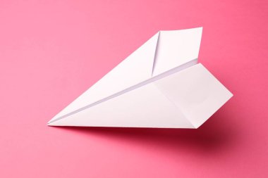Pembe arka planda el yapımı beyaz kağıt uçak