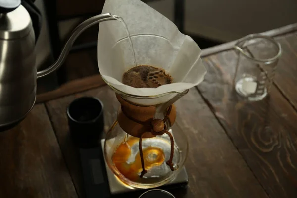 カフェの木製テーブルでコーヒーメーカーにお湯を注ぐバリスタ クローズアップ — ストック写真