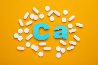 Haplar ve kalsiyum sembolü turuncu arka planda açık mavi harflerden yapılmıştır.