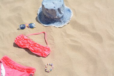 Kot şapka, güneş gözlüğü ve kumda bikini, mesaj için yer. Plaj aksesuarları