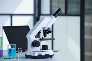Laboratuardaki beyaz masada cam kaydıraklı modern mikroskop, metin için boşluk
