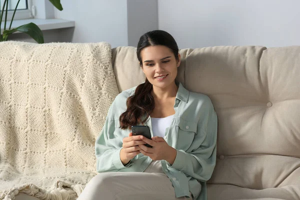 Νεαρή Γυναίκα Smartphone Που Κάθεται Στον Καναπέ Στο Σπίτι — Φωτογραφία Αρχείου