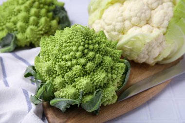 Taze Romanesco brokoli ve karnabahar beyaz fayanslı masada, yakın plan.