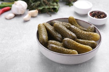 Açık gri masada salatalık turşusu ve malzemeler.