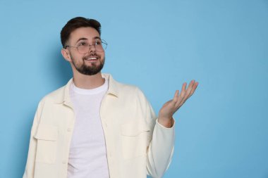 Açık mavi arka planda beyaz ceketli yakışıklı adam, metin için yer var.