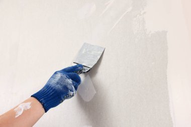 Duvara macun bıçağıyla sıva yapan adam, yakın plan. Ev yenilenmesi