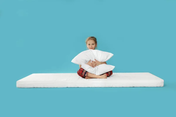 Kleines Mädchen Umarmt Kissen Auf Matratze Vor Hellblauem Hintergrund — Stockfoto