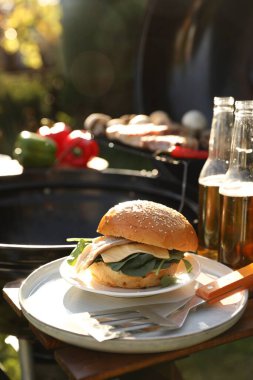 Barbekü ızgarasının yanındaki masada lezzetli bir burger. Metin için boşluk