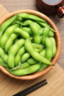 Tahta masada soya sosuyla servis edilen kabuklu yeşil edamame fasulyeleri.