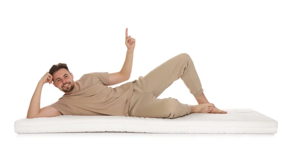 男人躺在柔软的床垫上 指向上方的白色背景 — 图库照片