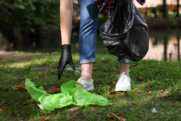 stock image Woman with plastic bag collecting garbage in park, closeup