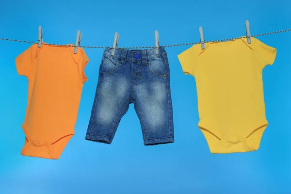 Çamaşır Ipinde Açık Mavi Arka Planda Farklı Bebek Kıyafetleri Kurutuluyor — Stok fotoğraf
